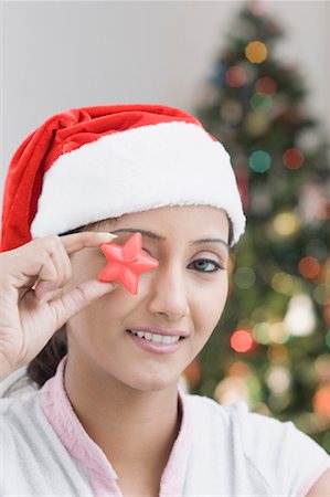 santa christmas hat women - Portrait of a young woman holding a star shaped candle in front of her eyes Stock Photo - Premium Royalty-Free, Code: 630-01491253