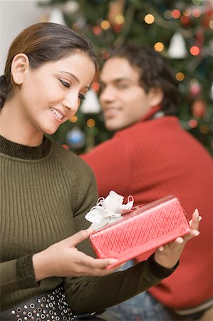 simsearch:630-01490862,k - Close-up of a young woman looking at a Christmas present with a young man sitting beside her Stock Photo - Premium Royalty-Free, Code: 630-01491265