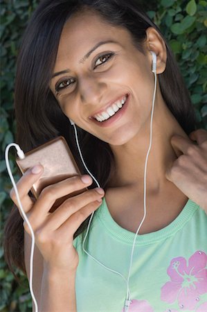 Portrait of a young woman listening to an MP3 player Stock Photo - Premium Royalty-Free, Code: 630-01491331