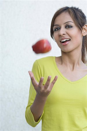 Portrait of a young woman tossing an apple Stock Photo - Premium Royalty-Free, Code: 630-01491359