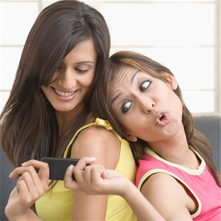 simsearch:630-01492890,k - Side profile of a young woman taking a mobile phone from her friend Foto de stock - Royalty Free Premium, Número: 630-01491352