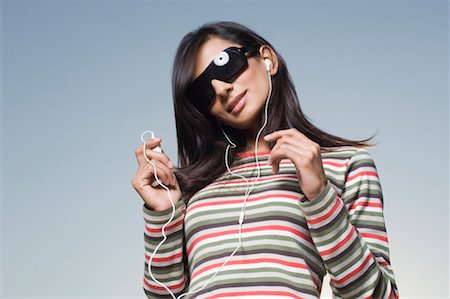 Low angle view of a young woman listening to an MP3 player Stock Photo - Premium Royalty-Free, Code: 630-01491373