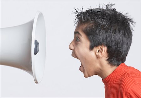 Close-up of a boy shouting in front of a megaphone Stock Photo - Premium Royalty-Free, Code: 630-01491545