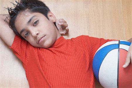 Portrait of a boy lying on a hardwood floor and holding a basketball Foto de stock - Sin royalties Premium, Código: 630-01491551