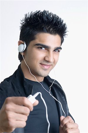 Portrait of a young man listening to an MP3 player Stock Photo - Premium Royalty-Free, Code: 630-01491592