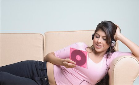 Young woman listening to music and holding a CD case Stock Photo - Premium Royalty-Free, Code: 630-01491609