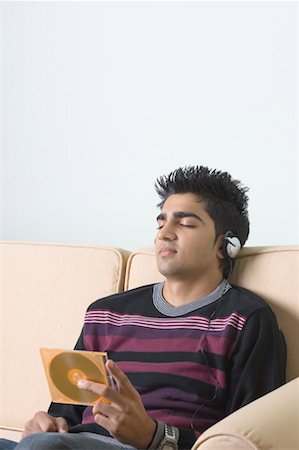 Young man listening to music and holding a CD case Stock Photo - Premium Royalty-Free, Code: 630-01491611