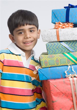 Portrait of a boy standing beside a stack of presents Stock Photo - Premium Royalty-Free, Code: 630-01491805