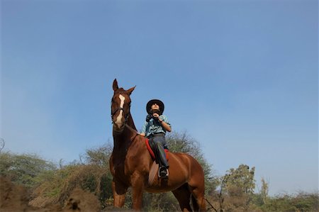 Low angle view of a teenage girl riding a horse and holding a pair of binoculars Stock Photo - Premium Royalty-Free, Code: 630-01491839