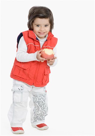 Portrait of a boy holding an apple and smiling Stock Photo - Premium Royalty-Free, Code: 630-01491912