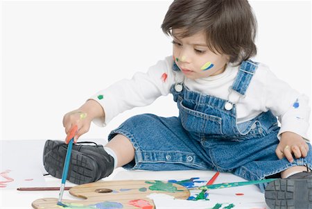 Boy sitting and painting with a paintbrush Foto de stock - Sin royalties Premium, Código: 630-01491935