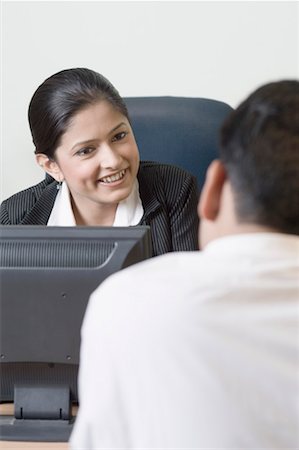 simsearch:630-01492147,k - Businesswoman sitting in front of a computer and talking to a businessman Stock Photo - Premium Royalty-Free, Code: 630-01492139