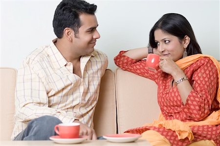 Young woman drinking a cup of tea with a young man looking at her Stock Photo - Premium Royalty-Free, Code: 630-01492146