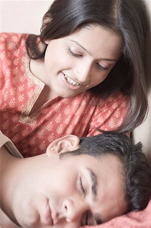 romantic pic husband wife sleep - Close-up of a young man sleeping on the bed and a young woman smiling behind him Stock Photo - Premium Royalty-Free, Code: 630-01492155