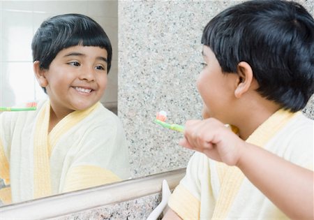 Girl holding a toothbrush looking at a mirror Stock Photo - Premium Royalty-Free, Code: 630-01492184