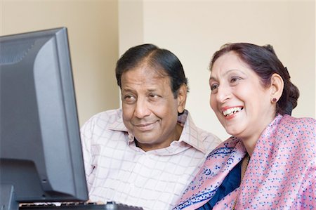 Close-up of a mature couple working on a computer and smiling Stock Photo - Premium Royalty-Free, Code: 630-01492213