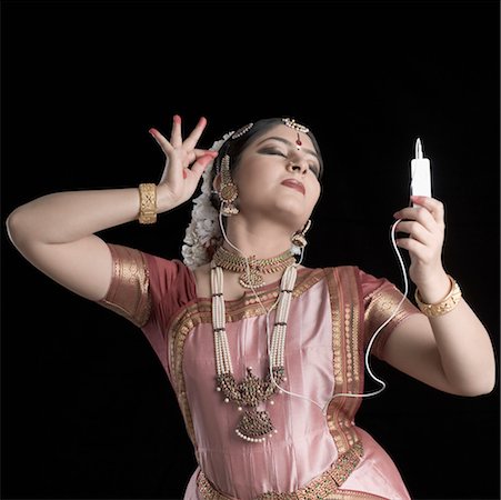 Young woman performing Bharatnatyam and listening to an MP3 player Stock Photo - Premium Royalty-Free, Code: 630-01492358