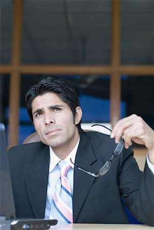 Businessman in front of a laptop and thinking Stock Photo - Premium Royalty-Free, Code: 630-01492596