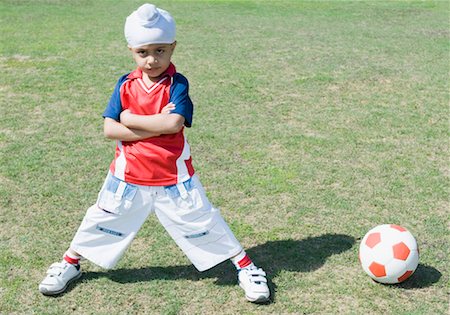 soccer boy length - Portrait of a boy standing near a soccer ball with his arms crossed Stock Photo - Premium Royalty-Free, Code: 630-01492630