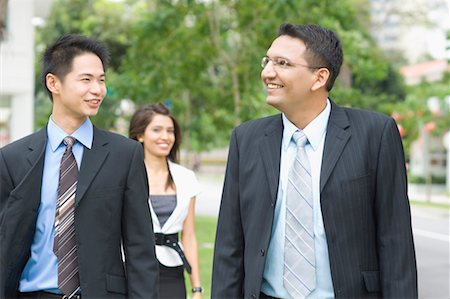 Close-up of two businessmen smiling with a businesswoman standing behind them Stock Photo - Premium Royalty-Free, Code: 630-01492715