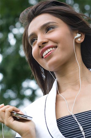 simsearch:630-01131178,k - Mid femme adulte écouter un lecteur MP3 et souriant Photographie de stock - Premium Libres de Droits, Code: 630-01492738