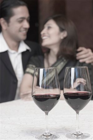 simsearch:630-01492926,k - Close-up of two wine glasses with a mid adult man and a young woman smiling in the background Stock Photo - Premium Royalty-Free, Code: 630-01492964