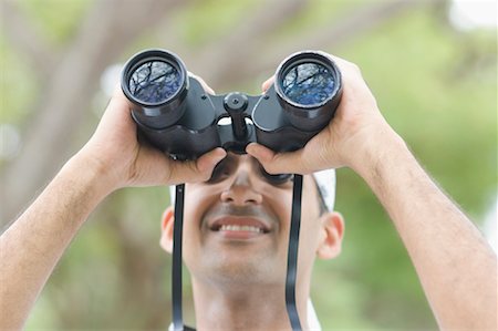 Close-up of a young man looking through a pair of binoculars Stock Photo - Premium Royalty-Free, Code: 630-01493010