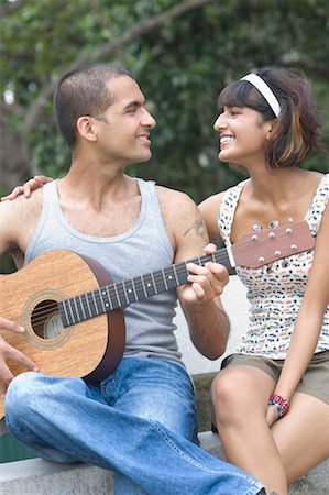 short adult - Close-up of a young man playing a guitar with a mid adult woman sitting beside him Stock Photo - Premium Royalty-Free, Code: 630-01493027