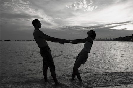 Silhouette of a couple holding hands and standing on the beach Stock Photo - Premium Royalty-Free, Code: 630-01493062