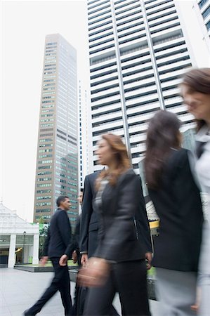 people walking on road side - Low angle view of business executives walking on the road with skyscrapers in the background, Singapore Stock Photo - Premium Royalty-Free, Code: 630-01707785