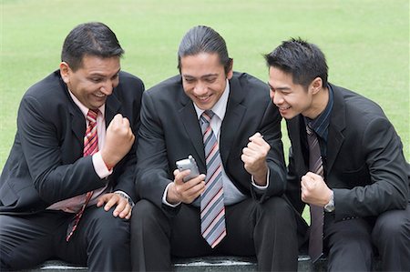 Three businessmen looking at a mobile phone and smiling Stock Photo - Premium Royalty-Free, Code: 630-01707780