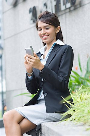 Side profile of a businesswoman using a palmtop and smiling Stock Photo - Premium Royalty-Free, Code: 630-01707781