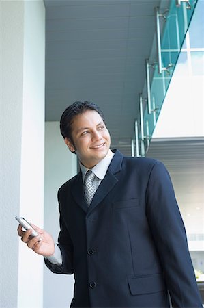 simsearch:630-02219583,k - Businessman holding a mobile phone and smiling Stock Photo - Premium Royalty-Free, Code: 630-01707851