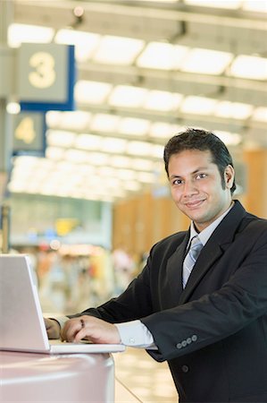 simsearch:630-01877048,k - Portrait of a businessman using a laptop at an airport Foto de stock - Sin royalties Premium, Código: 630-01707895