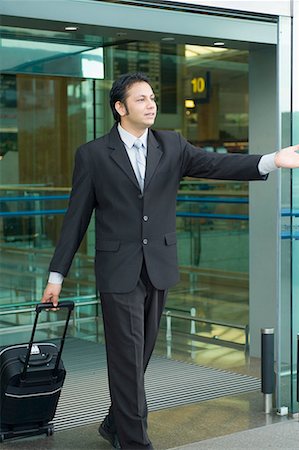 simsearch:630-02219583,k - Businessman pulling luggage and hailing a taxi at an airport Stock Photo - Premium Royalty-Free, Code: 630-01707917