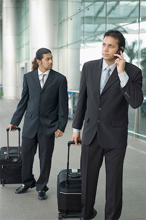 Two businessmen standing at an airport with their luggage and waiting Stock Photo - Premium Royalty-Free, Code: 630-01707918