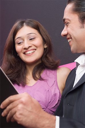 service man shoulder - Couple holding a menu and smiling Stock Photo - Premium Royalty-Free, Code: 630-01707938