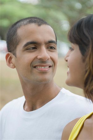 Side profile of a young couple looking at each other and smiling Stock Photo - Premium Royalty-Free, Code: 630-01708002