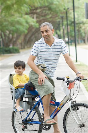 sit on the road boy images - Mid adult man riding a bicycle with his son sitting behind him Stock Photo - Premium Royalty-Free, Code: 630-01708024