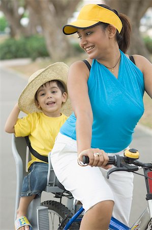 sun care - Mid adult woman riding a bicycle with her son sitting behind her Stock Photo - Premium Royalty-Free, Code: 630-01708060