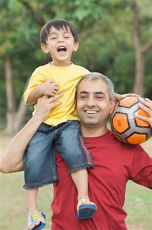 soccer boys sit on the ball - Mid adult man carrying his son on his shoulder and holding a soccer ball Stock Photo - Premium Royalty-Free, Code: 630-01708072