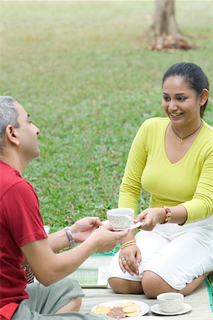 Mid adult woman giving a tea cup to a mid adult man and smiling Stock Photo - Premium Royalty-Free, Code: 630-01708096