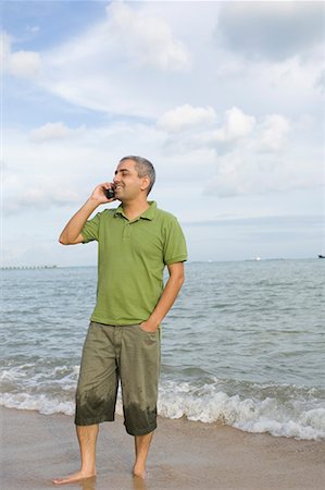 Mid adult man standing on the beach and talking on a mobile phone Stock Photo - Premium Royalty-Free, Code: 630-01708158