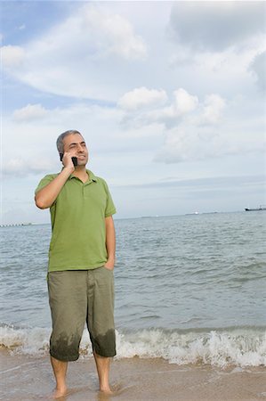 simsearch:630-01877039,k - Mid adult man standing on the beach and talking on a mobile phone Fotografie stock - Premium Royalty-Free, Codice: 630-01708159