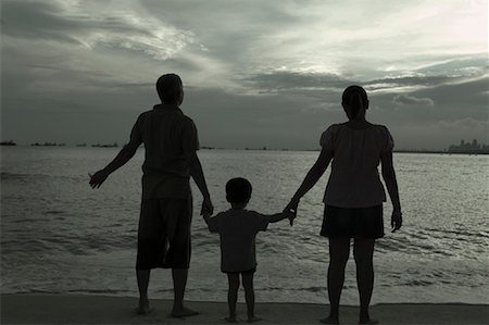 father and son silhouette - Rear view of a mid adult couple standing on the beach with their son and holding hands Stock Photo - Premium Royalty-Free, Code: 630-01708179