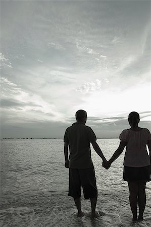 Rear view of a mid adult couple holding hands on the beach at dusk Stock Photo - Premium Royalty-Free, Code: 630-01708180