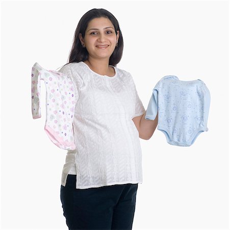 Portrait of a young woman holding baby clothing Stock Photo - Premium Royalty-Free, Code: 630-01708204