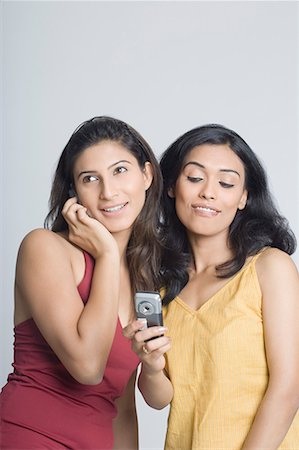 Young woman talking on a mobile phone and another young woman reading a message Stock Photo - Premium Royalty-Free, Code: 630-01708566