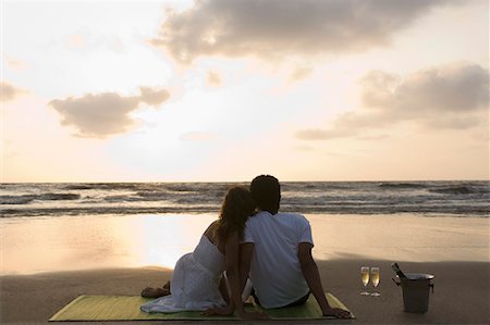 romantic beach sunset - Rear view of a young couple sitting on a picnic blanket Stock Photo - Premium Royalty-Free, Code: 630-01708635