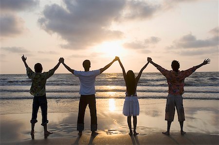 sun up - Rear view of three young men and a young woman standing side by side with holding hands on the beach Stock Photo - Premium Royalty-Free, Code: 630-01708638